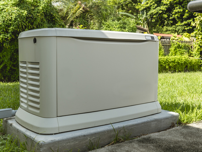 A Home Standby Generator installed at the backyard of a house. An air-cooled natural gas or liquid propane generator for residential use.