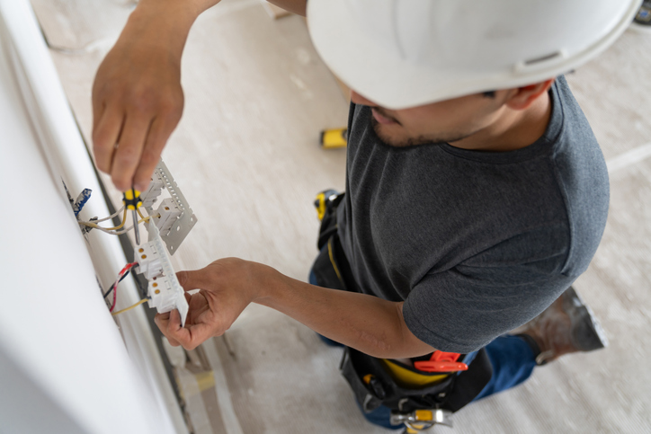 High angle view of an electrician installing a power socket while working at a construction site